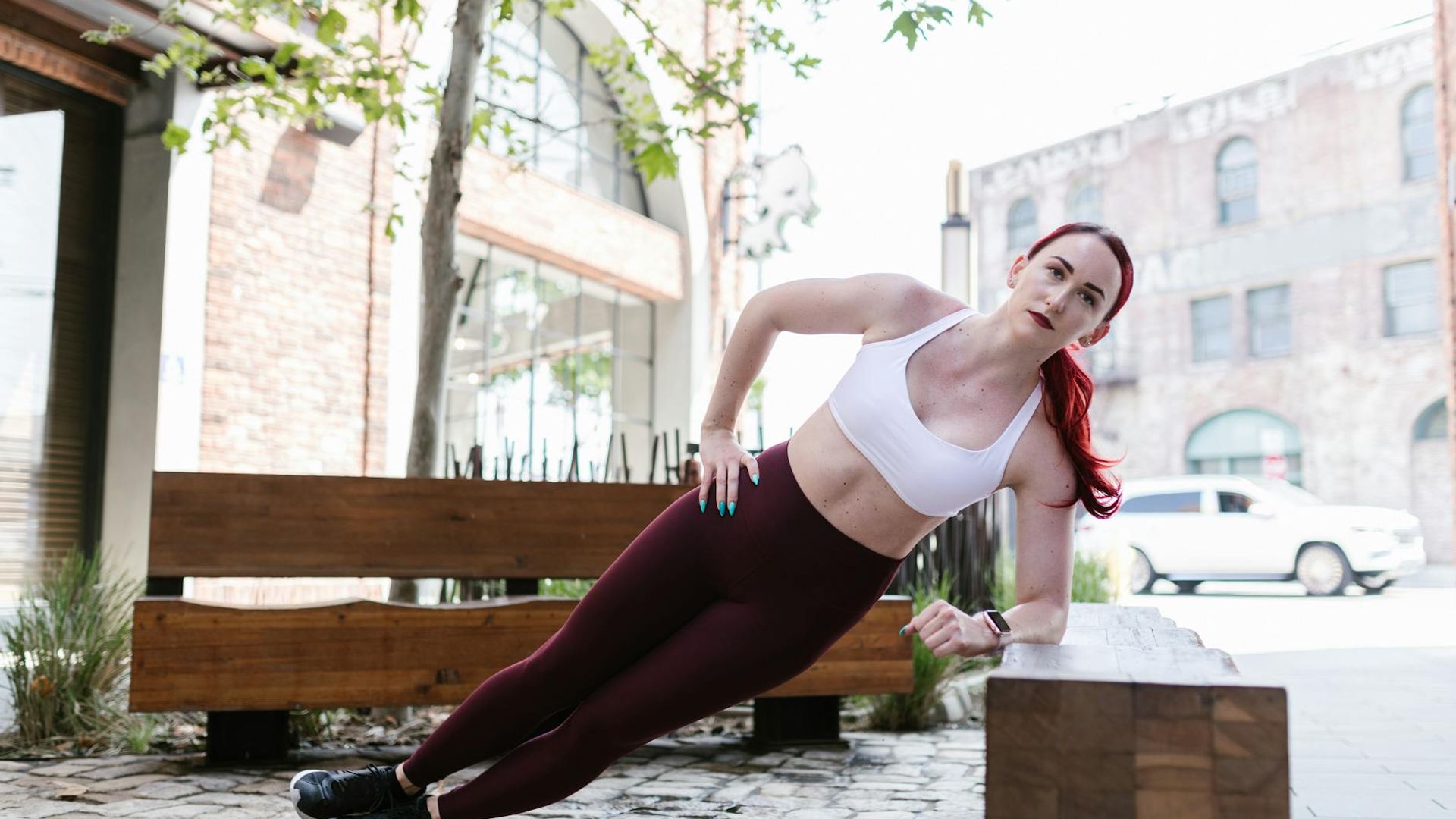 Woman performing a side plank exercise in dark studio environment